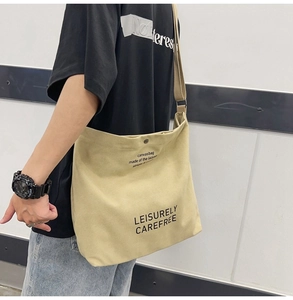Close-up of large canvas crossbody bag with printed text worn by a model