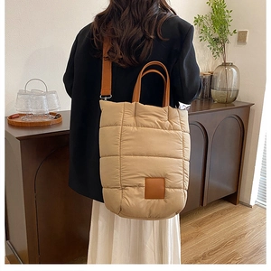 Quilted beige puffer tote bag featuring square padding and adjustable shoulder strap