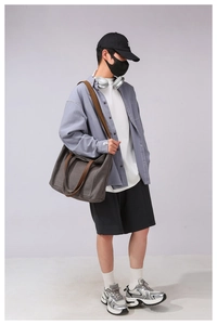 Detail of dark grey canvas tote bag showing the contrast leather handles and strap