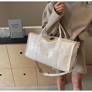Detalle de bolsa de viaje de cuero sintético blanco con logo NOCO y correa ajustable