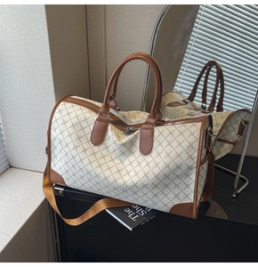 Detail der Reisetasche mit geometrischem Muster, braunen Griffen und Silberbeschlägen