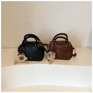 Detail of two mini Boston bags in black and brown with cute bear charm and golden hardware