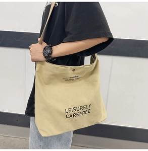 Detail of beige canvas crossbody bag with artistic Leisurely Carefree printed text