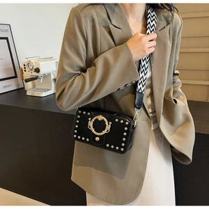 Detail einer Vintage-Schultertasche aus schwarzem Leder mit goldener Schnalle und Webriemen