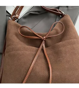 Close-up of matte brown suede tote bag featuring a glossy patent leather bow detail