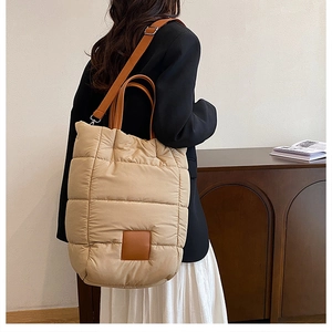 Detail of beige quilted bucket bag showing leather handles and adjustable strap