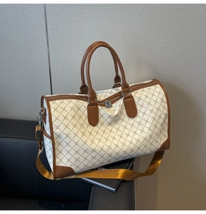 Detail einer beigen Reisetasche mit geometrischem Muster, Lederbesatz und Tragegurt