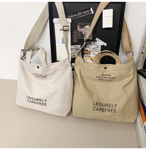 Detail of canvas tote bags in beige and khaki with adjustable straps and snap closure