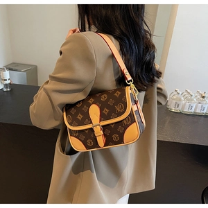 Detailaufnahme der Retro-Monogramm-Umhängetasche mit breitem Gurt und Goldakzenten