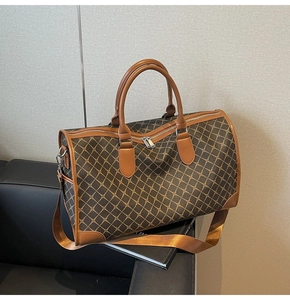 Detail einer großen braunen Reisetasche mit geometrischem Muster auf einem Sofa