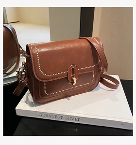 Vue détaillée d'un sac vintage en cuir marron avec clous dorés sur un livre blanc