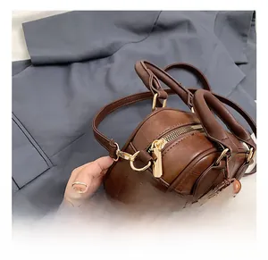Close-up of brown leather crossbody bag with gold hardware and a cute plush charm