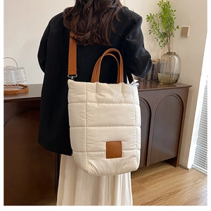 Close-up of white quilted puffer tote bag with brown leather handles and strap