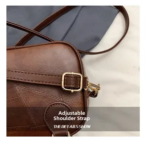 Close-up of adjustable shoulder strap with gold metal buckle on brown leather crossbody bag