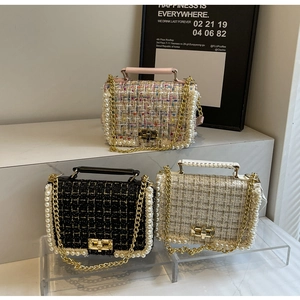 Close-up of stylish tweed flap bags with pearl borders and gold metal chain straps