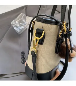 Detail of bucket bag with gold hardware, leather trim, and brown fluffy keychain