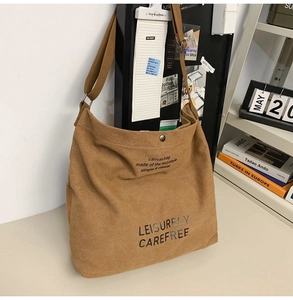 Detail of large canvas crossbody bag with text print on minimalist desk setting