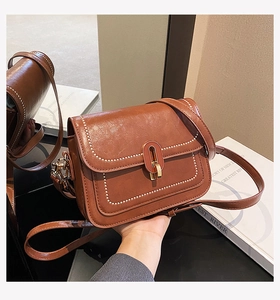 Vue détaillée du sac marron avec bordure cousue et fermoir rotatif doré élégant