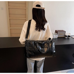 Bolso de viaje grande de cuero negro usado por un modelo en un interior de estilo moderno