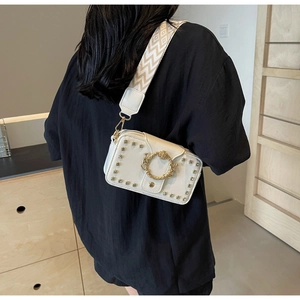 Details der weißen Leder-Schultertasche mit Goldnieten und Drachenschnalle