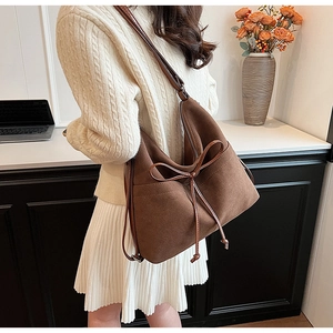 Close-up of brown suede hobo bag featuring a slim leather bow detail and shoulder strap