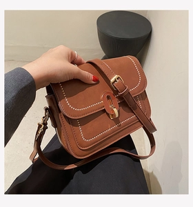 Détail du sac bandoulière caramel avec surpiqûres contrastées et fermoir doré ovale