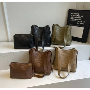 Détail de sacs seaux tressés en noir, vert, marron et beige avec pochettes intérieures