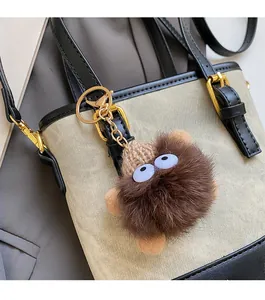Close-up of a plush cartoon charm with a brown knit hat on a bucket bag strap