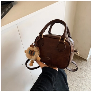 Close-up of retro brown leather handbag with quilting and plush alpaca charm