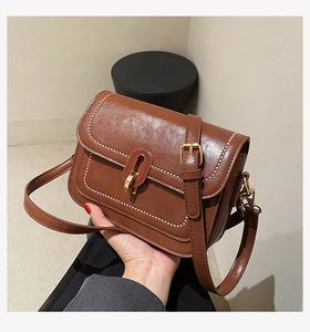 Détail du sac vintage en cuir marron avec texture premium et fermoir métallique doré