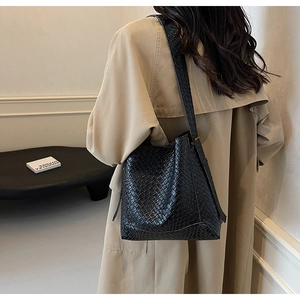 Détail du sac à bandoulière tressé noir avec motif en damier et design forme seau