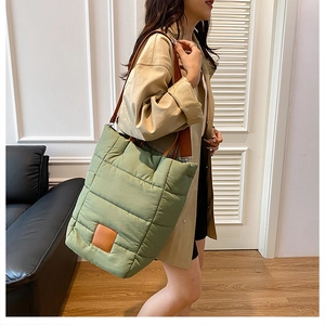 Close-up of quilted nylon bucket bag in sage green with brown leather shoulder strap