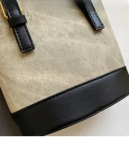 Detail of canvas texture and black leather stitching with gold hardware on bucket bag