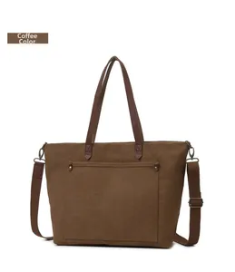 Detalle de un bolso tote de lona marrón con asas de cuero y correa ajustable para hombro