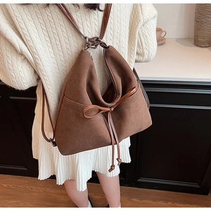 Detail of dark brown faux suede backpack with bow accent and slim leather straps
