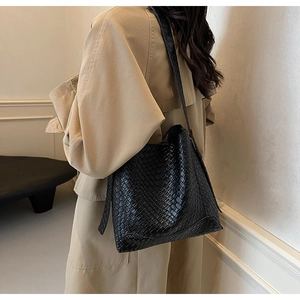 Détail du sac seau noir texturé porté sur un trench-coat beige élégant et chic