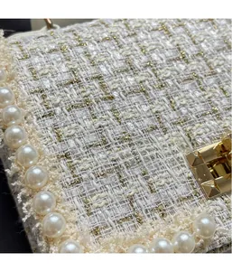 Close-up of tweed fabric texture with faux pearl trim and golden stud metal lock