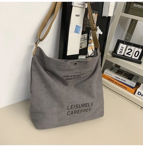 Macro detail of dark grey canvas crossbody bag with khaki strap and button closure