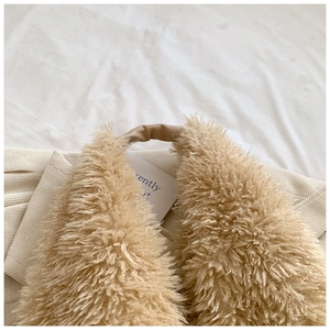 Detailed close-up of fluffy plush tote bag featuring soft beige fur and brown leather handles