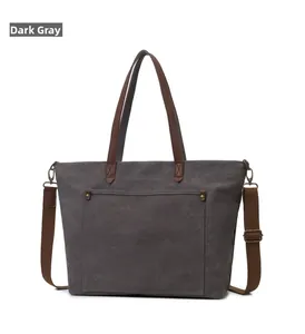 Detalle del bolso tote de lona gris oscuro con asas de cuero marrón y correa ajustable