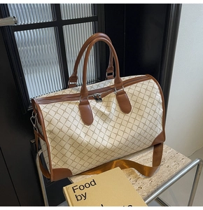 Detail der karierten Reisetasche mit Ledergriffen und strukturiertem Rautenmuster
