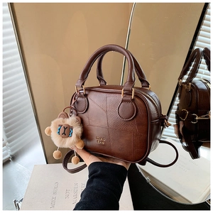 Close-up of brown vintage pillow bag featuring lion plush charm and gold brand logo