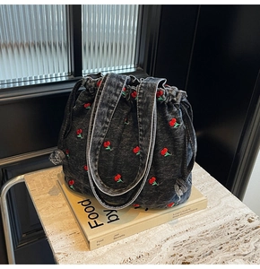 Detailed view of cherry embroidery on dark grey washed denim bucket bag with drawstring