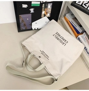 Close-up of large canvas tote bag with black artistic text print and sturdy straps