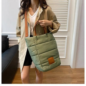 Close-up of olive green quilted puffer bucket bag with brown leather handles and strap