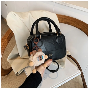 Detail of black patchwork Boston bag with gold hardware and a cute plush bear charm
