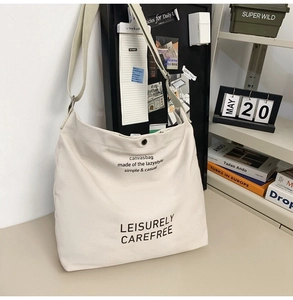 Close-up of off-white canvas bag with Leisurely Carefree text and premium metal hardware