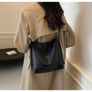 Détail du sac cabas noir à motif crocodile porté avec un trench-coat de couleur kaki