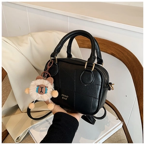 Close-up of black PU leather pillow bag with geometric stitching and bear charm