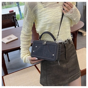 Detailansicht einer Vintage-Denim-Umhängetasche mit Metallnieten und Gurt am Modell